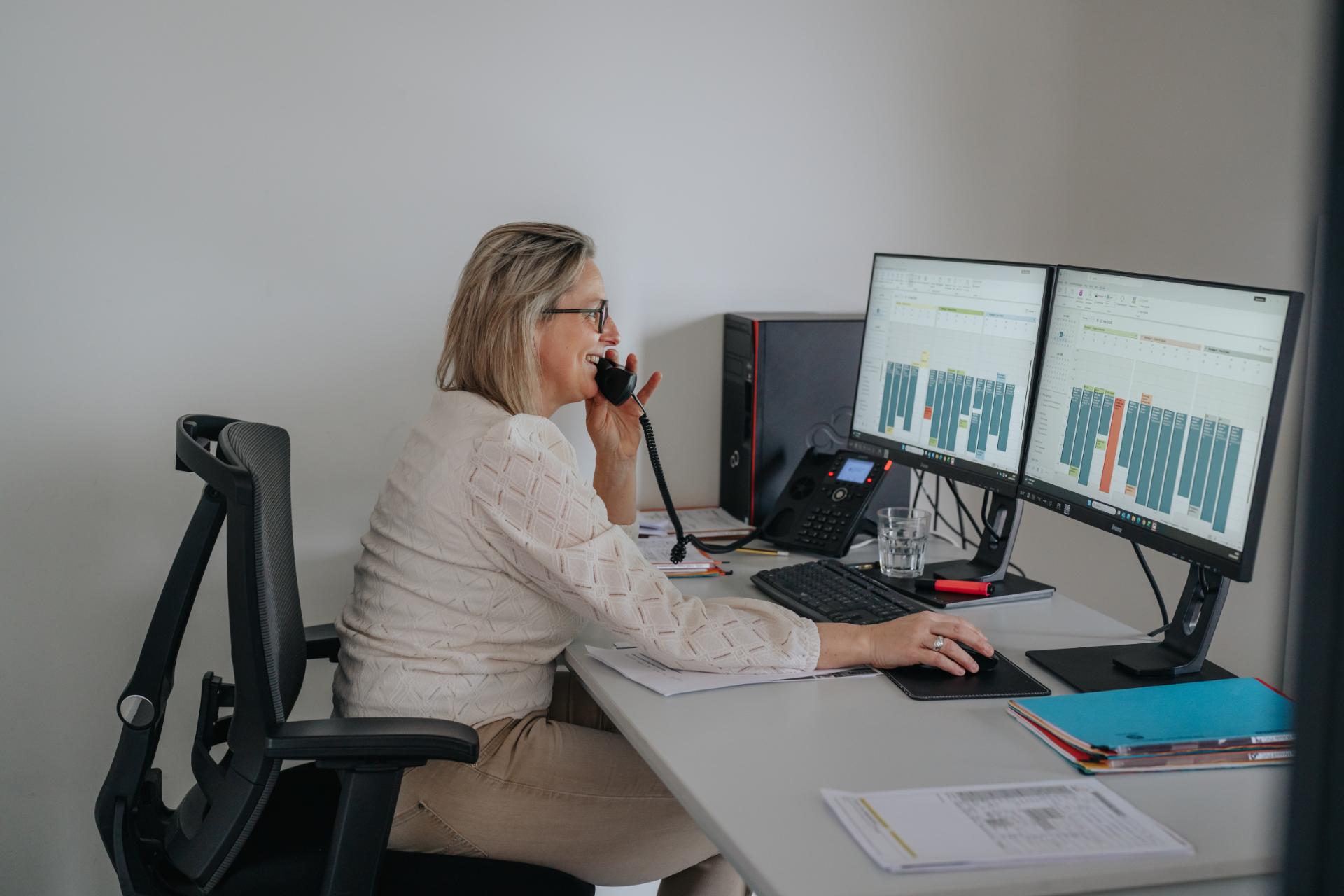 Medewerker van Het Ramenhuis aan de telefoon op kantoor